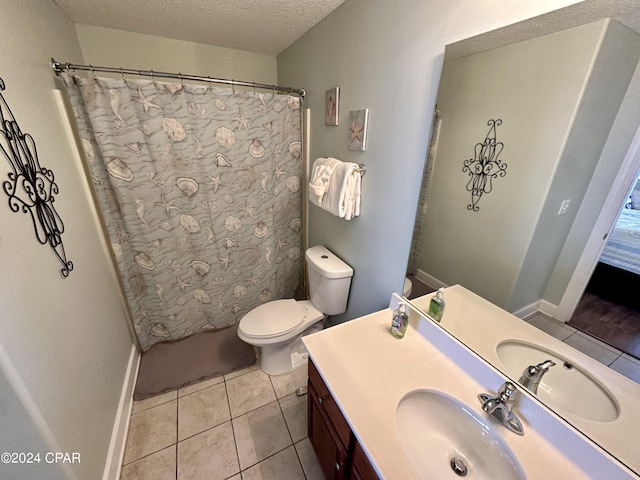 bathroom with tile floors, toilet, large vanity, and a textured ceiling