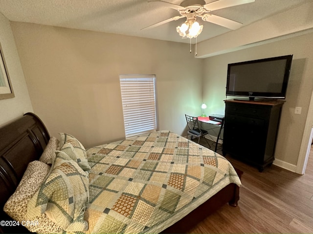 bedroom featuring dark hardwood / wood-style flooring, ceiling fan, and a textured ceiling