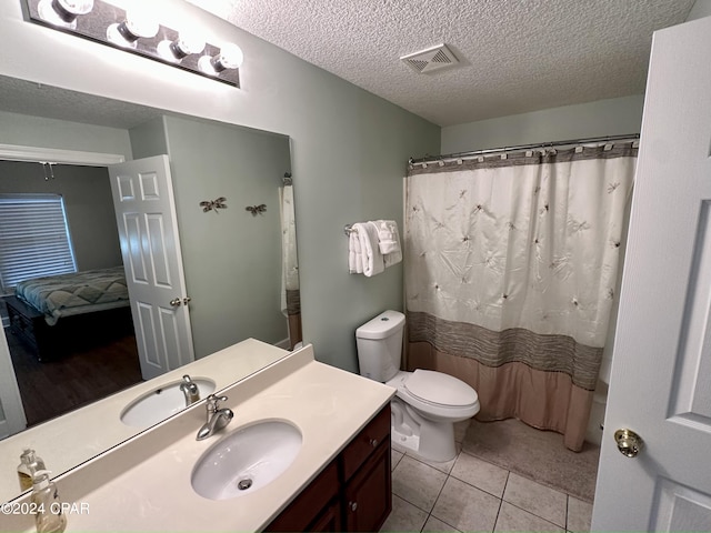 bathroom with toilet, tile flooring, vanity, and a textured ceiling