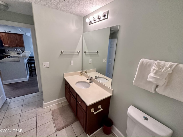 bathroom with a textured ceiling, large vanity, toilet, and tile flooring