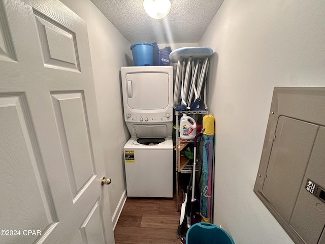 laundry area featuring dark hardwood / wood-style flooring, a textured ceiling, and stacked washer / drying machine