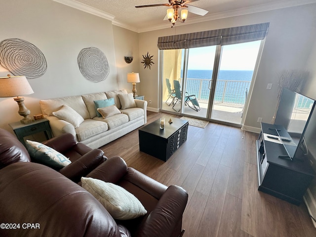 living room with a water view, wood-type flooring, ceiling fan, and ornamental molding