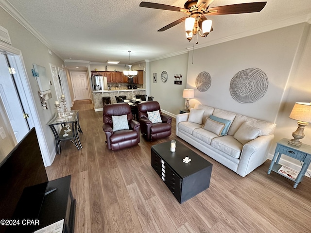 living room with ornamental molding, light hardwood / wood-style flooring, ceiling fan, and a textured ceiling