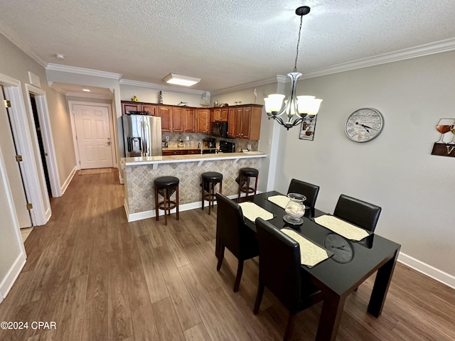 dining space with ornamental molding, a textured ceiling, dark hardwood / wood-style floors, and a notable chandelier