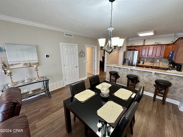 dining area with dark hardwood / wood-style floors, crown molding, an inviting chandelier, and a textured ceiling