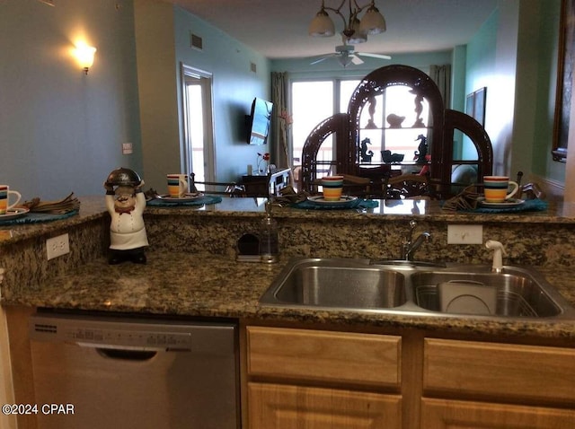 kitchen featuring stainless steel dishwasher, sink, ceiling fan, and dark stone countertops