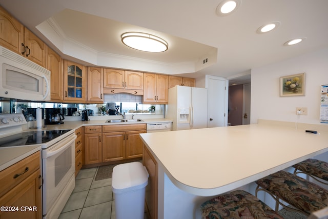 kitchen featuring light tile flooring, a breakfast bar, white appliances, a tray ceiling, and sink