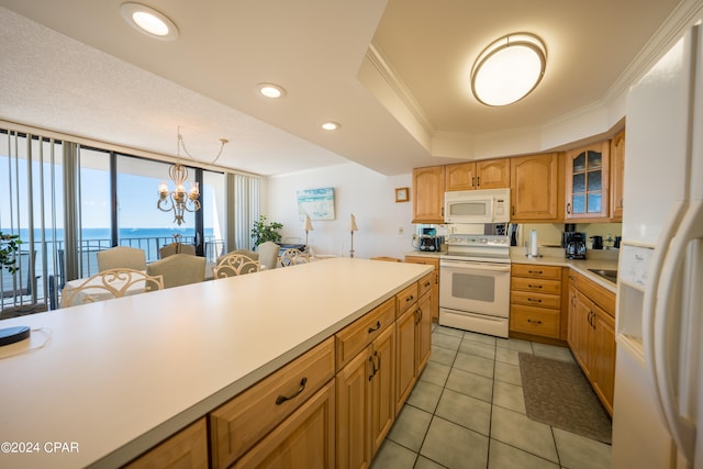 kitchen featuring white appliances, pendant lighting, ornamental molding, a chandelier, and a water view