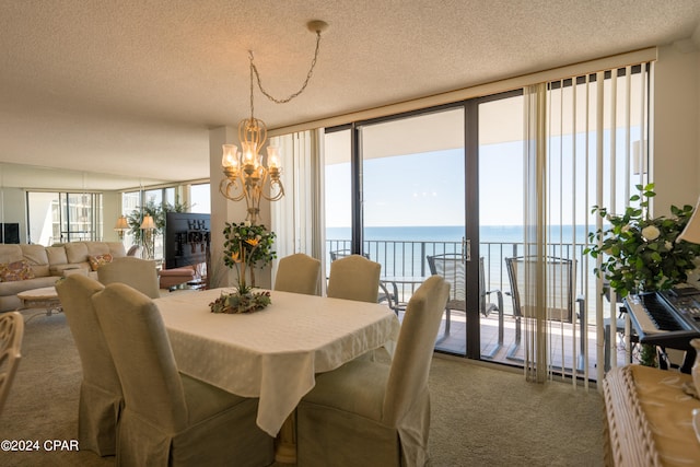 carpeted dining room with a water view, a notable chandelier, a textured ceiling, and a wealth of natural light