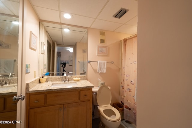 bathroom with a paneled ceiling, toilet, and vanity