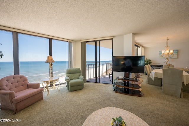 living room with a notable chandelier, a textured ceiling, carpet, and a water view