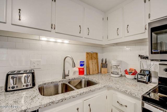 kitchen with sink, stainless steel appliances, backsplash, and white cabinets