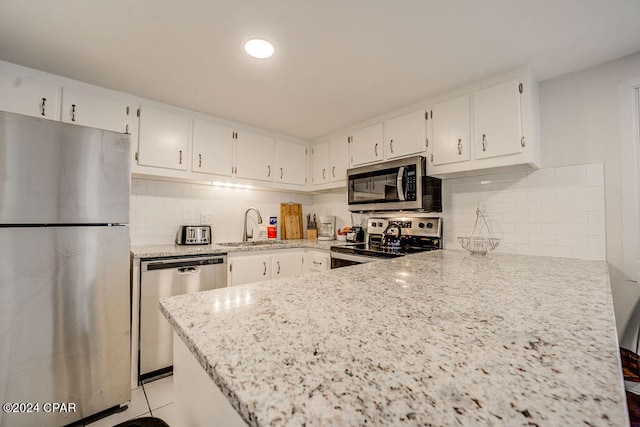 kitchen with white cabinets, tasteful backsplash, and stainless steel appliances