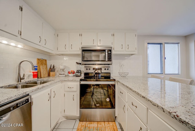 kitchen with stainless steel appliances, light hardwood / wood-style flooring, light stone countertops, backsplash, and sink