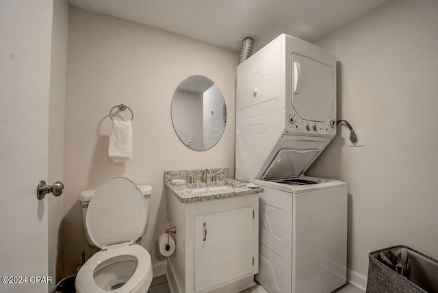 bathroom featuring vanity, stacked washing maching and dryer, tile floors, and toilet