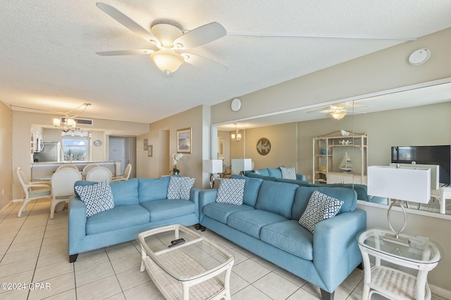 living room featuring a textured ceiling, ceiling fan with notable chandelier, and light tile flooring