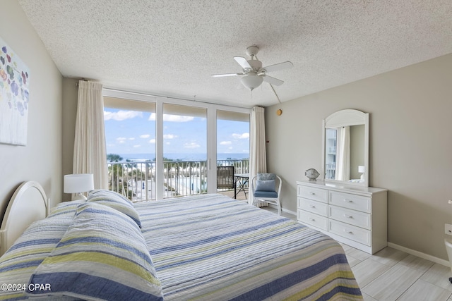 bedroom featuring access to outside, a textured ceiling, ceiling fan, and a wall of windows