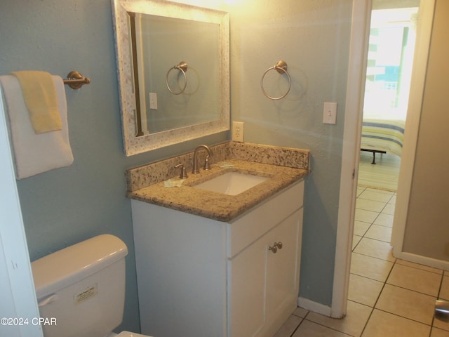 bathroom with tile flooring, vanity with extensive cabinet space, and toilet