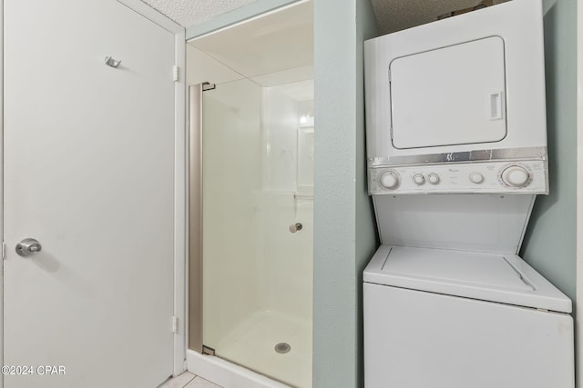 laundry room with a textured ceiling and stacked washing maching and dryer