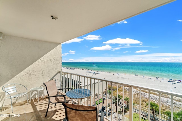 balcony with a water view and a view of the beach