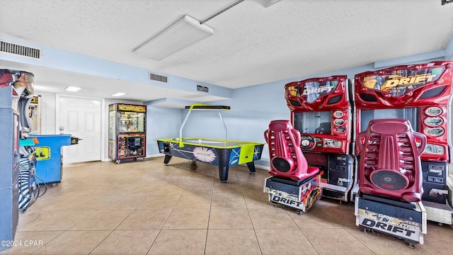 recreation room with light tile flooring and a textured ceiling