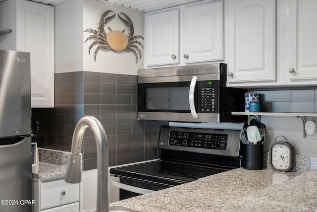 kitchen featuring white cabinets, appliances with stainless steel finishes, tasteful backsplash, and light stone countertops