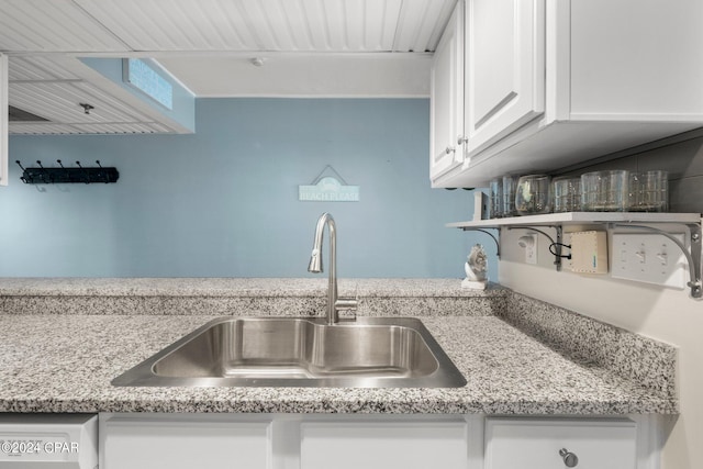 kitchen with white cabinetry, sink, and light stone counters