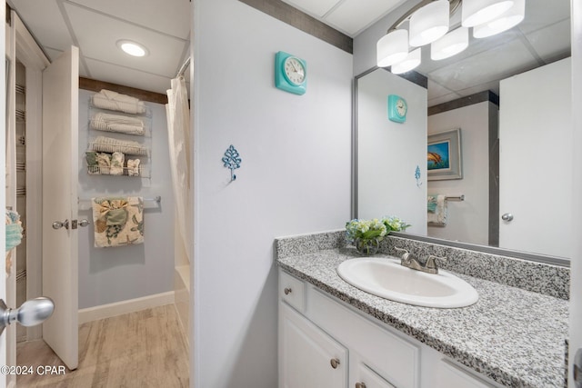 bathroom with shower / bath combination with curtain, hardwood / wood-style floors, vanity, and a drop ceiling