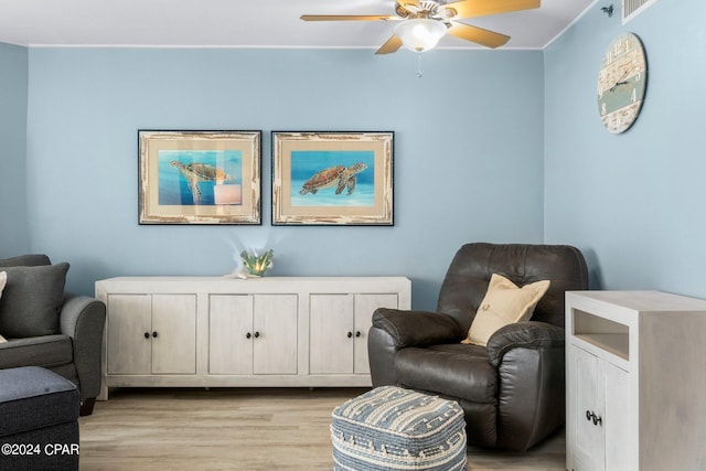 living area featuring crown molding, light hardwood / wood-style floors, and ceiling fan