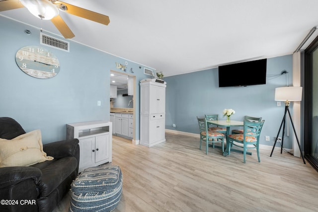 living room with ceiling fan, light wood-type flooring, and sink