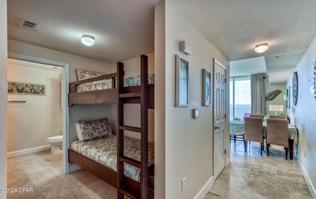 tiled bedroom with connected bathroom and a textured ceiling