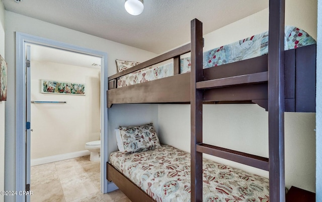 tiled bedroom featuring connected bathroom and a textured ceiling