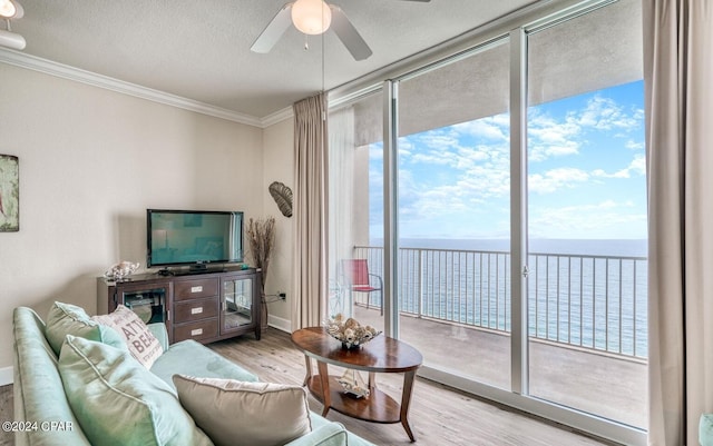 living room with ornamental molding, ceiling fan, a water view, and light wood-type flooring