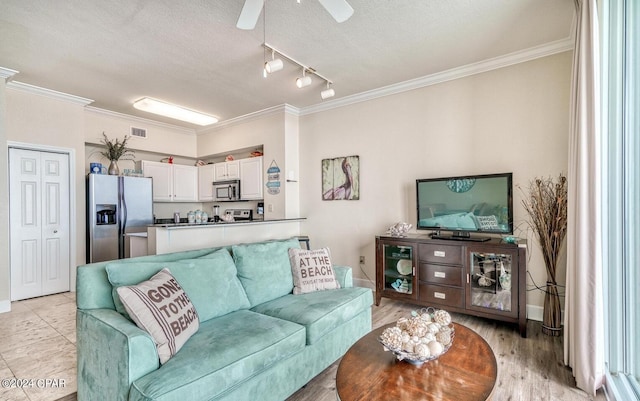 living room with a textured ceiling, rail lighting, ceiling fan, and ornamental molding