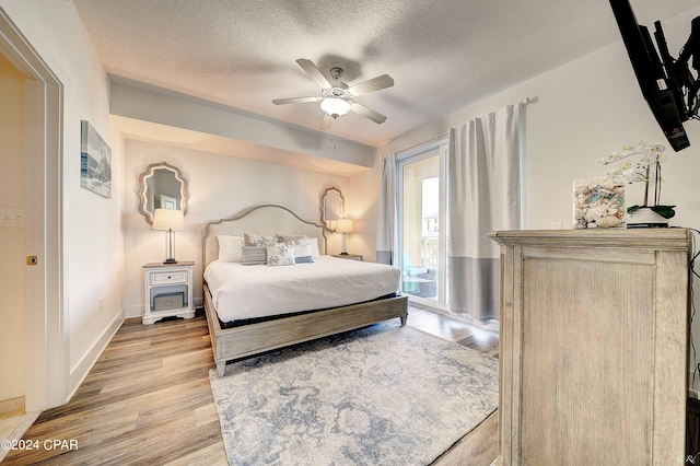 bedroom featuring light hardwood / wood-style flooring, ceiling fan, access to outside, and a textured ceiling