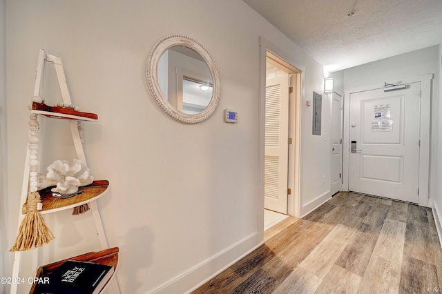 hall with light wood-type flooring and a textured ceiling