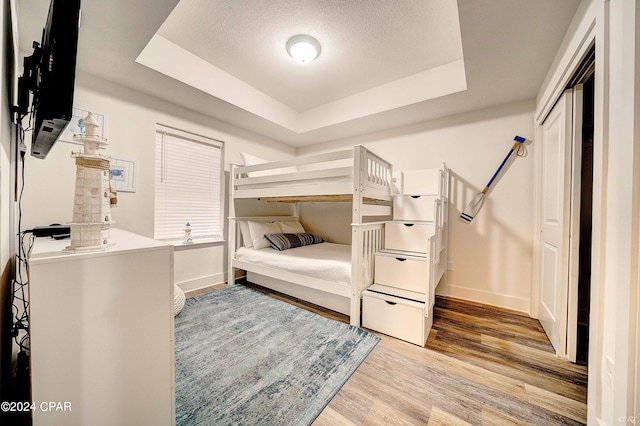 bedroom featuring hardwood / wood-style floors, a closet, and a tray ceiling