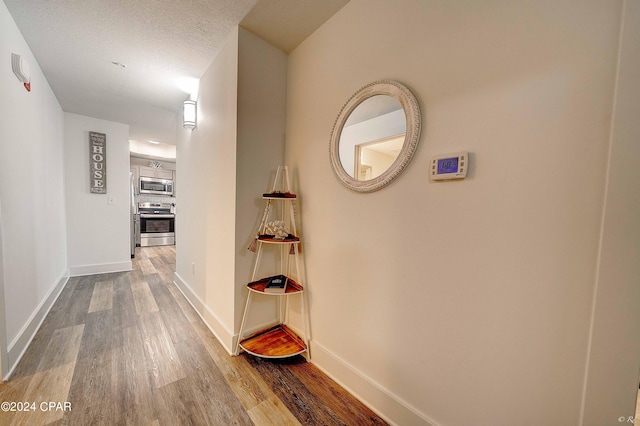 corridor featuring wood-type flooring and a textured ceiling