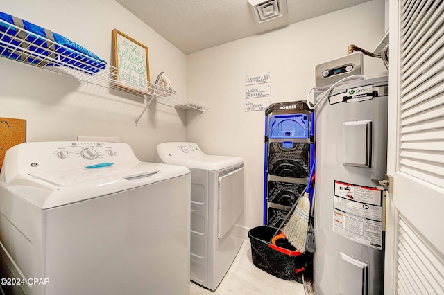 clothes washing area featuring water heater, independent washer and dryer, and a textured ceiling