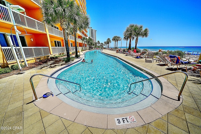 view of pool with a water view and a patio area