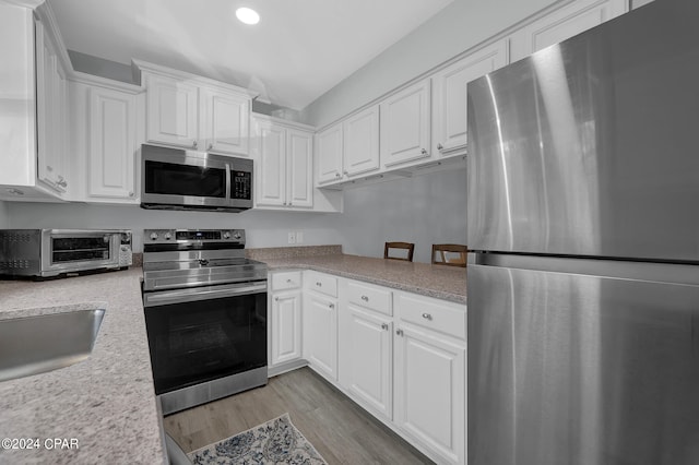 kitchen featuring appliances with stainless steel finishes, white cabinetry, and light hardwood / wood-style floors