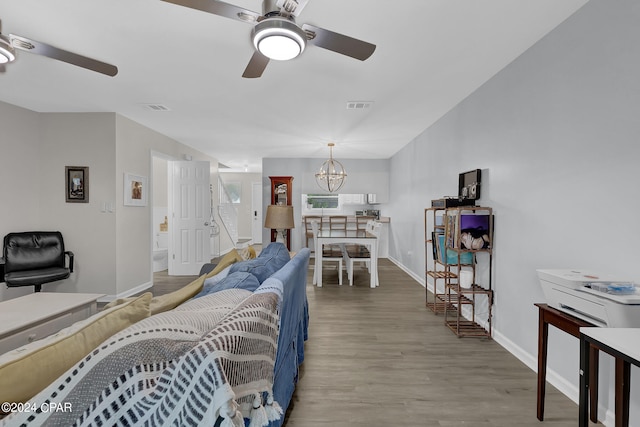 living room featuring ceiling fan with notable chandelier and light wood-type flooring