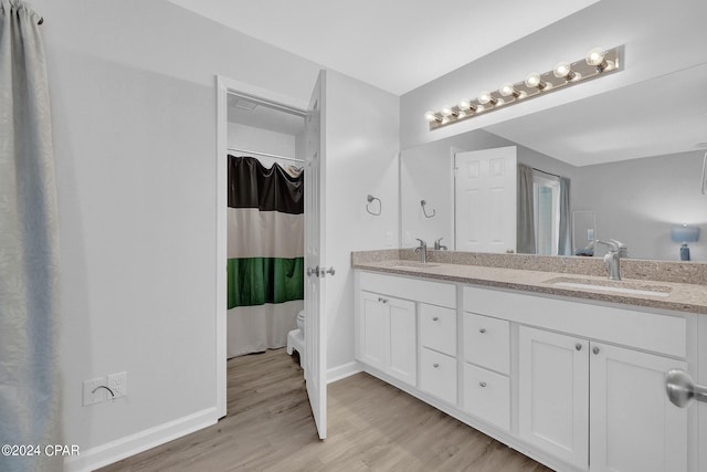 bathroom featuring double sink vanity, toilet, and hardwood / wood-style floors