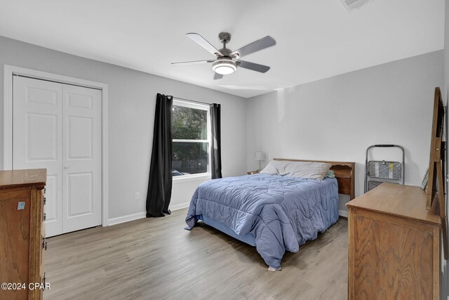 bedroom with a closet, light hardwood / wood-style floors, and ceiling fan