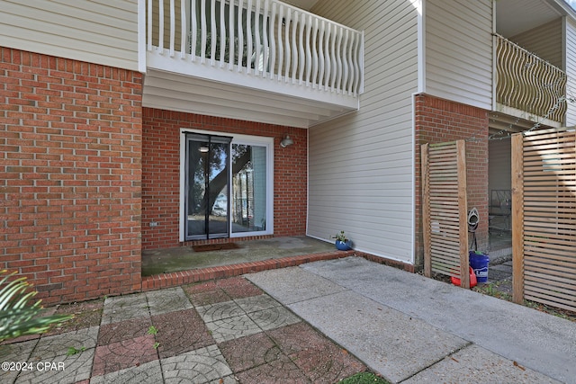 view of exterior entry with a balcony and a patio