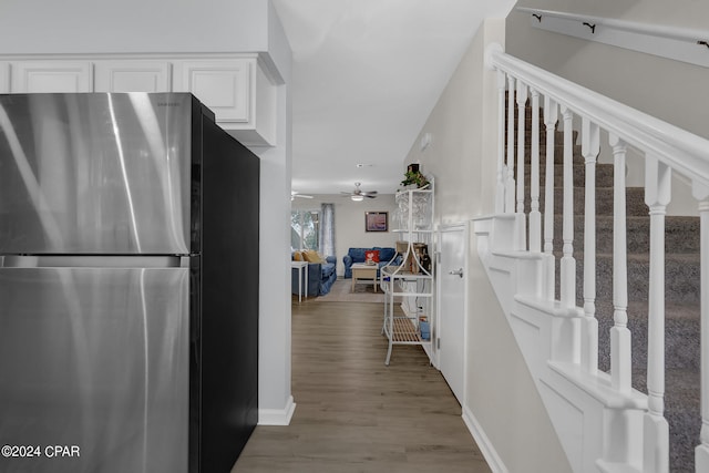 interior space with stainless steel fridge, white cabinets, ceiling fan, and light hardwood / wood-style flooring