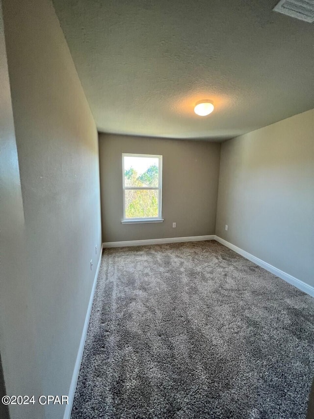 empty room featuring dark colored carpet and a textured ceiling