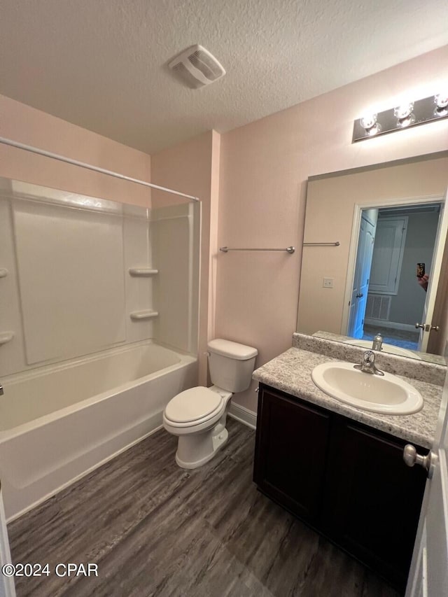 full bathroom with toilet, bathing tub / shower combination, a textured ceiling, vanity, and hardwood / wood-style floors