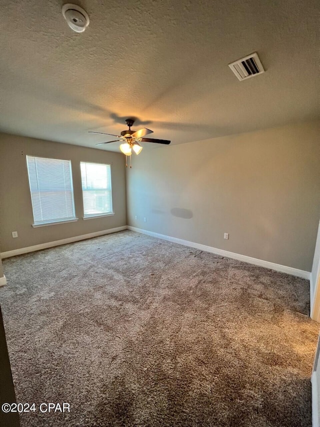 spare room featuring a textured ceiling, carpet, and ceiling fan