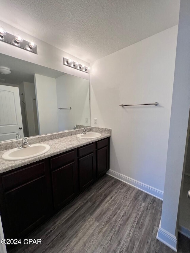 bathroom featuring double vanity, a textured ceiling, and wood-type flooring